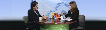 Two individuals speaking at a table, completing an interview